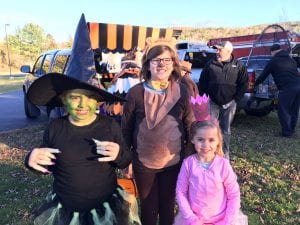 Students in costumes at the trunk or treat. Witch, bear and princess.