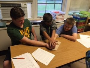 students use hands to melt ice cube to get a penny during Perseverence Activity