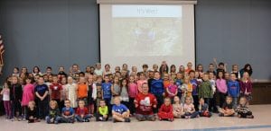 John Robinson sitting and smiling at the end of the speech with elementary students